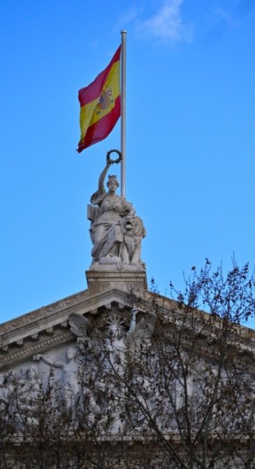Monument espagnol sous le drapeau de l'Espagne, symbole de la langue espagnole enseignée chez Merlo Skills Group.